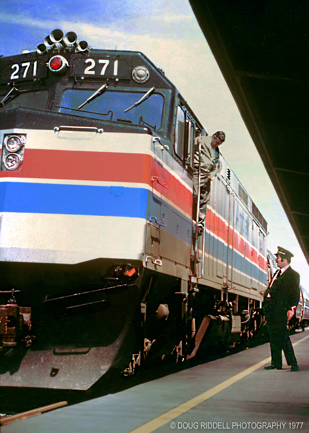 blue and red striped gray locomotive with conductor on side
