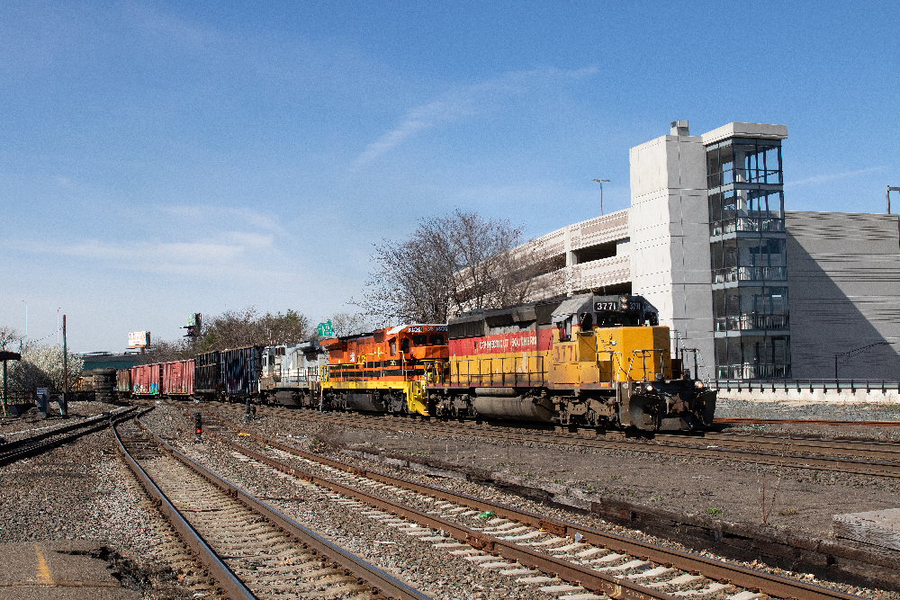A red and yellow diesel locomotive and a orange and yellow unit pulling a freight train.