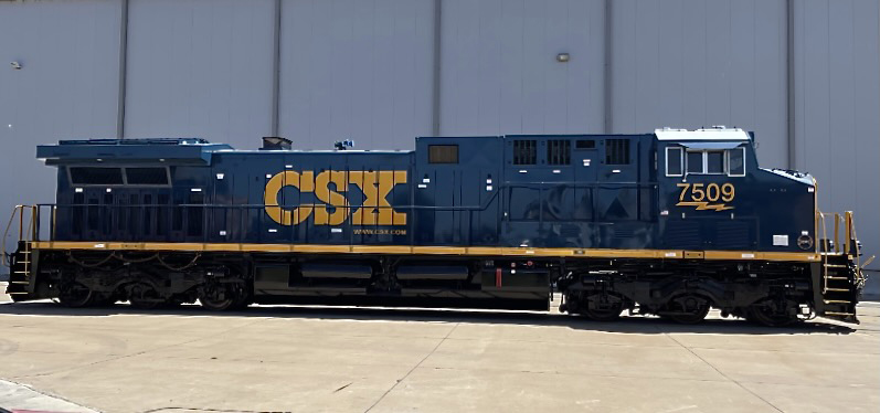 Blue and yellow locomotive outside shop building