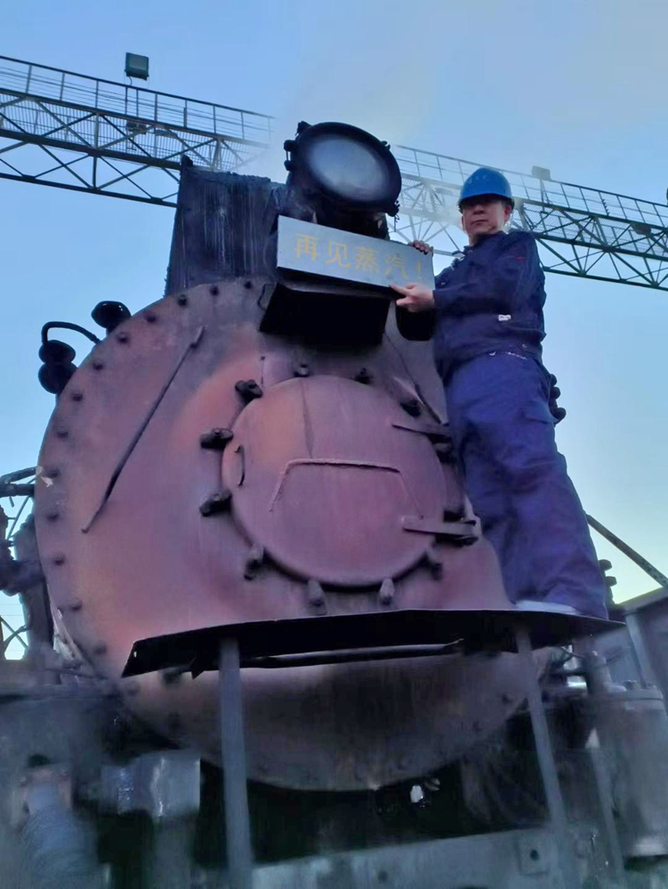 Man at front of steam locomotive holding sign