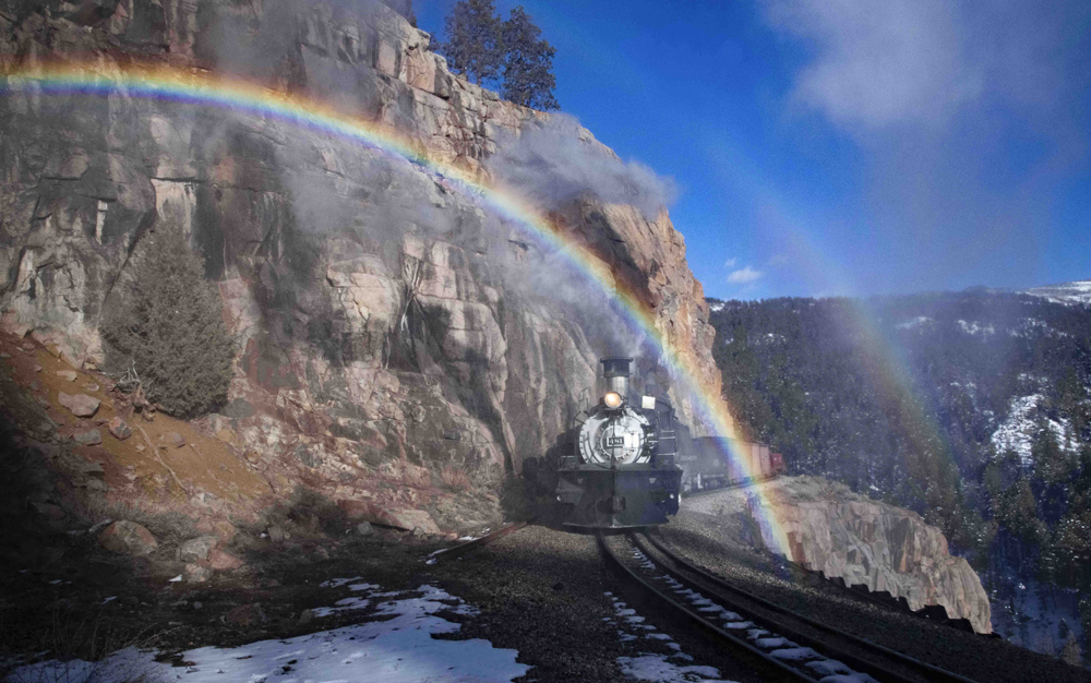 Steam locomotive framed by rainbows