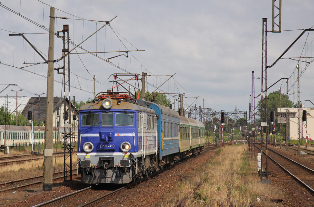 Passenger train with blue locomotive and two different kinds of passenger cars