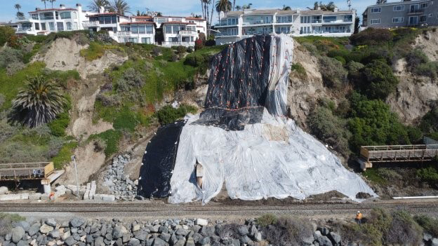 Landslide next to railroad tracks covered by tarps