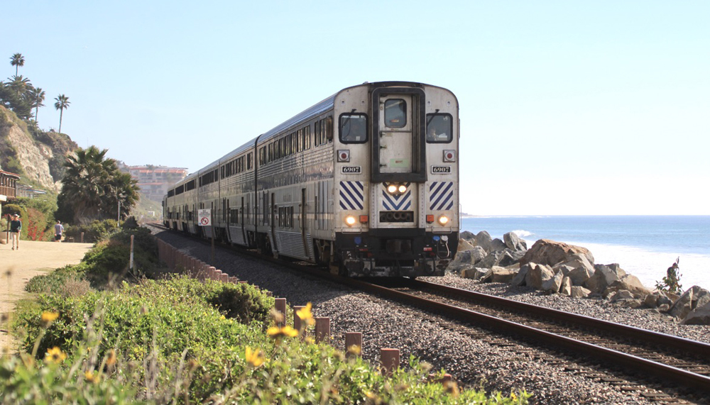 Cab car leads passenger train along track next to ocean