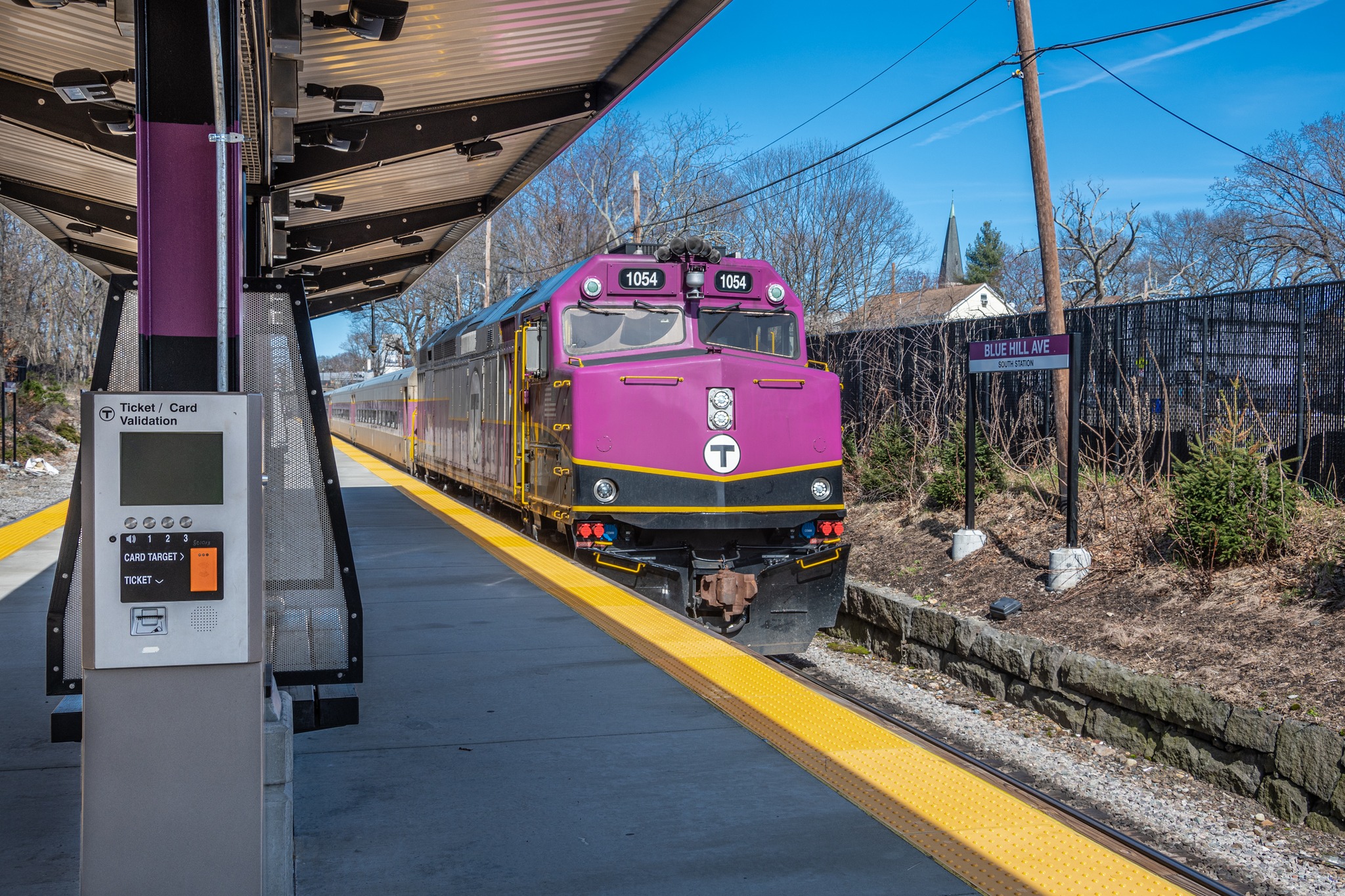 Commuter rail train with purple locomotive arrives at station