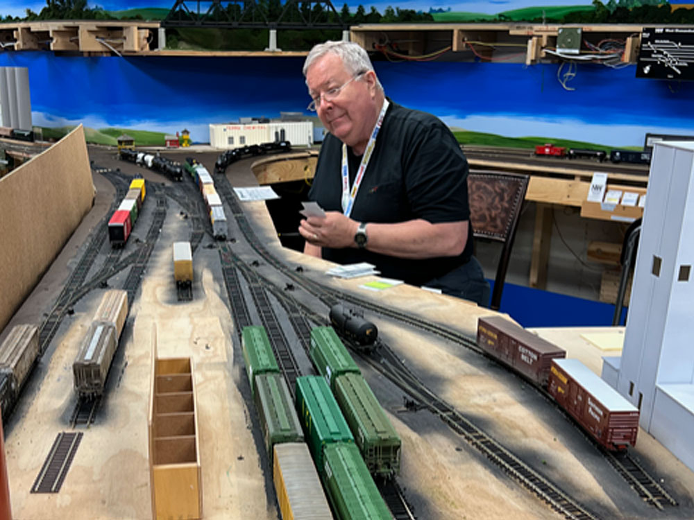 A man sorts car cards while working an HO scale train yard