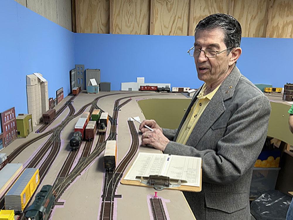  A man consults a clipboard while looking at an HO scale model railroad: Tips for operating session success