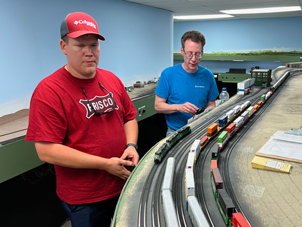 Two men operate trains on an HO scale model railroad]