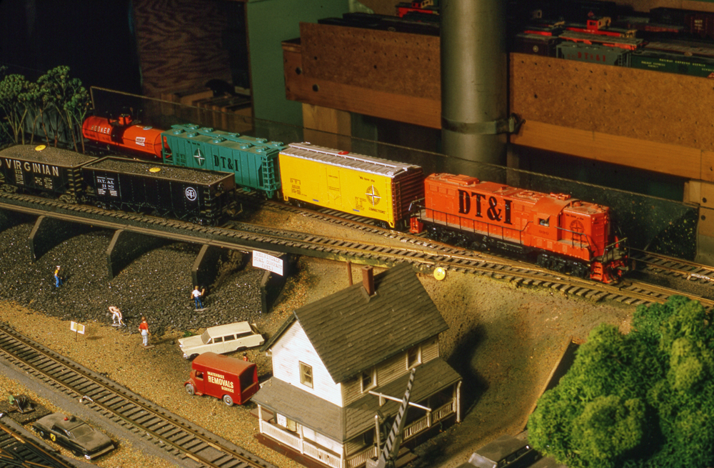 Color photo of freight train passing a trestle and office.
