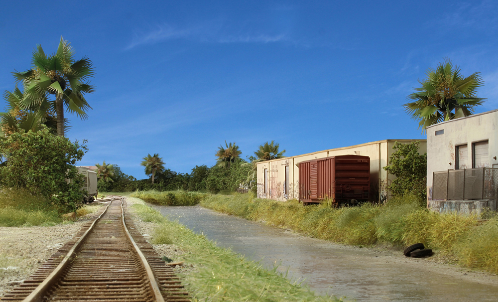 Picture of a canal scene on a model railroad with boxcars parked near warehouses.