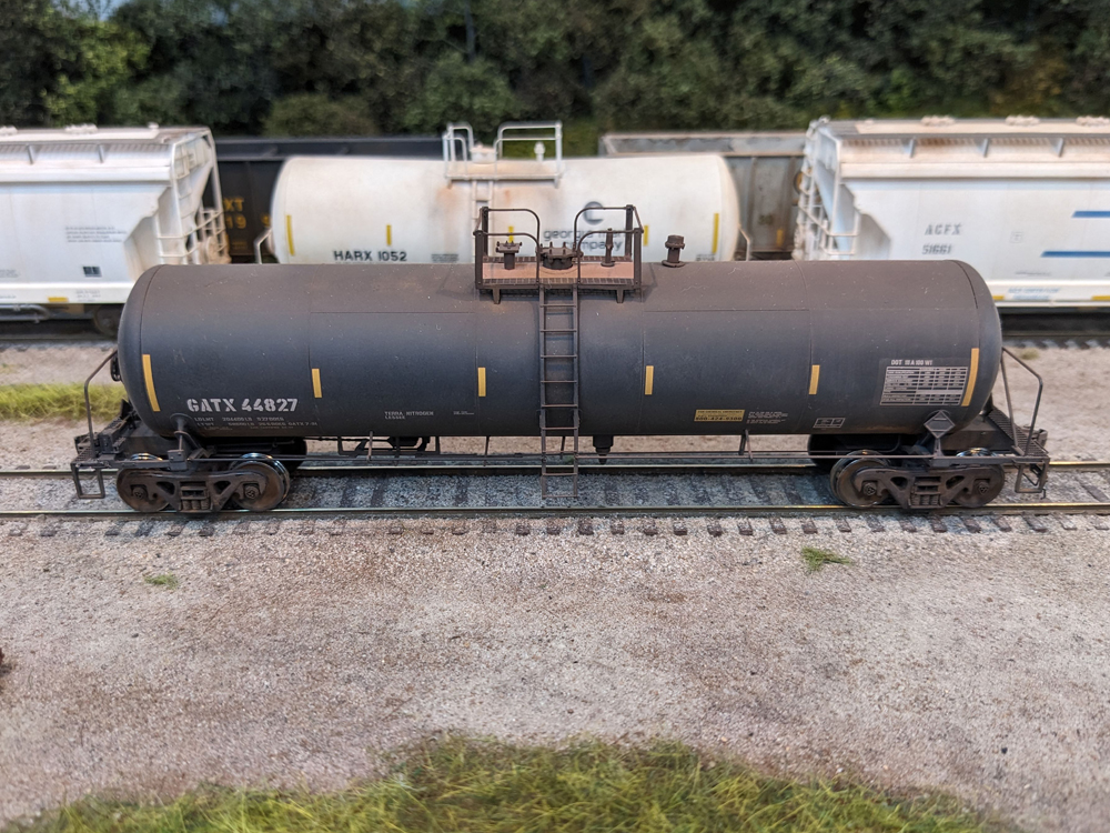 Color photo of weathered HO scale tank car on model railroad.