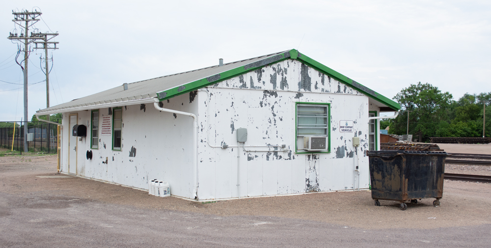 Color photo of metal building with peeling green and white paint.