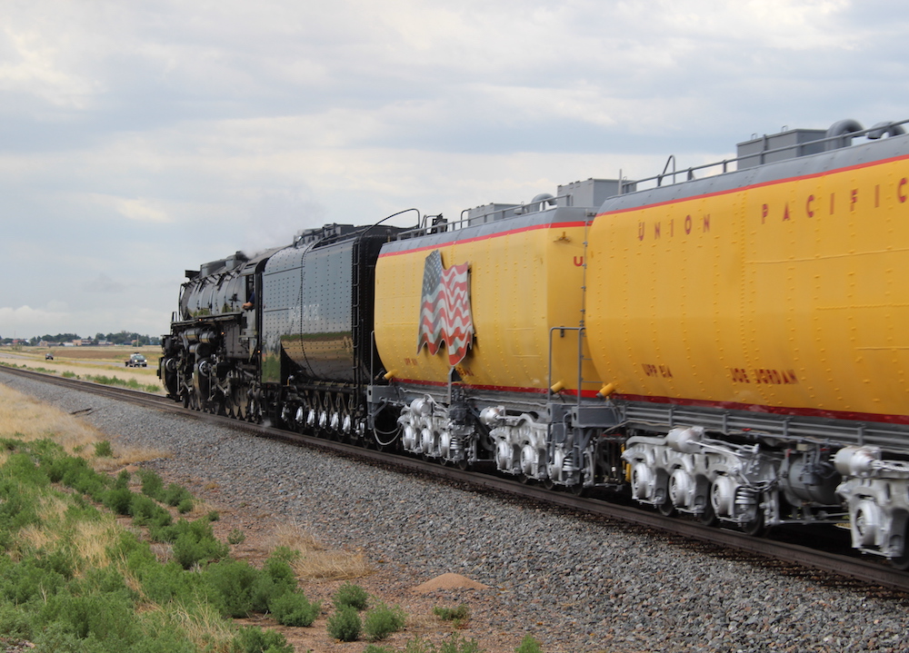 Two, yellow auxiliary water cars riding behind a big steam locomotive.