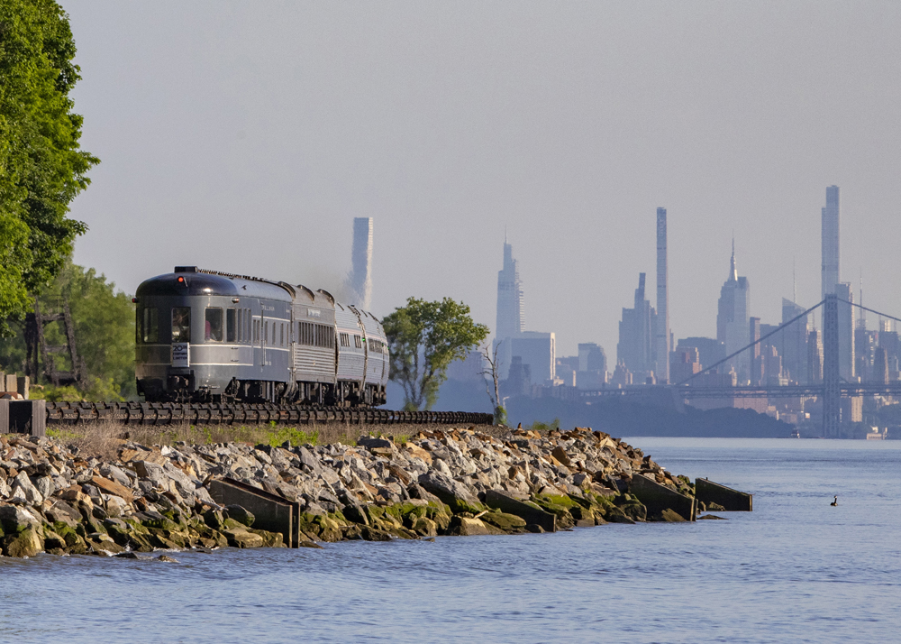Heritage observation car on back of Amtrak train, with New York skyline in the distance. 