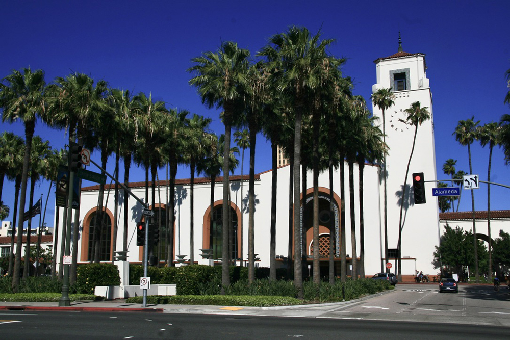 Spanish-style passenger station with palm trees in foreground