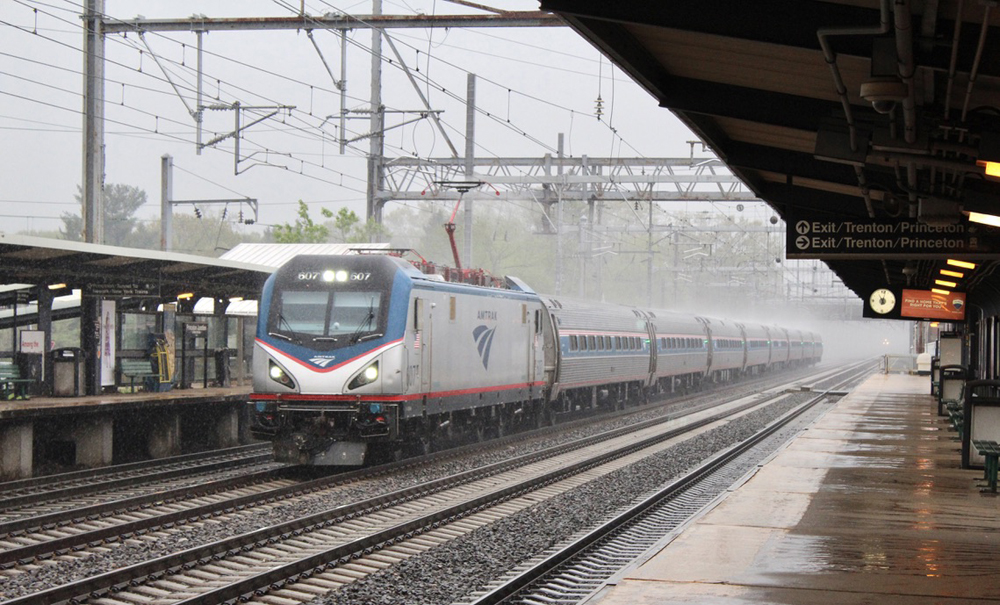 Passenger train passing through station in heavy rain