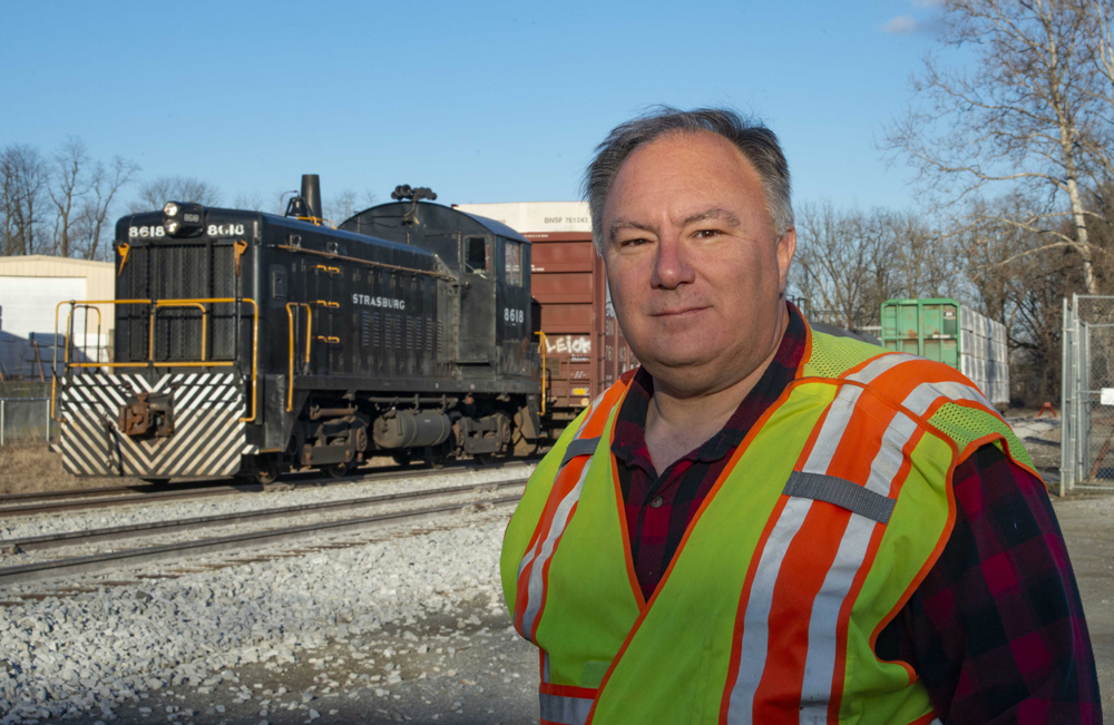 Man in hi-visibilty vest with diesel switcher in background