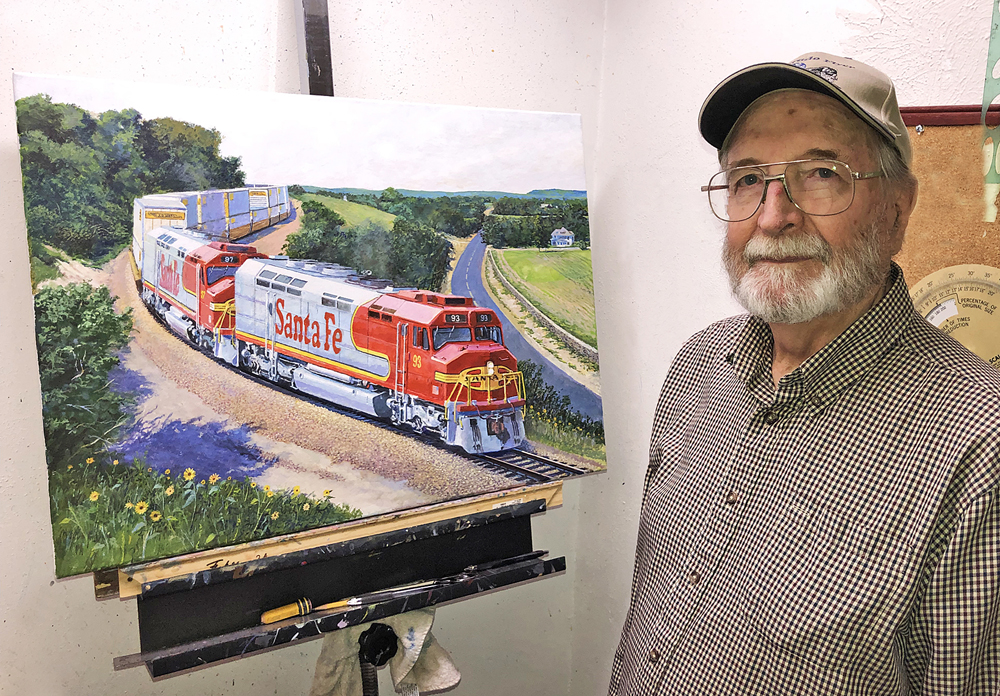 Man standing next to painting of diesel locomotives on 