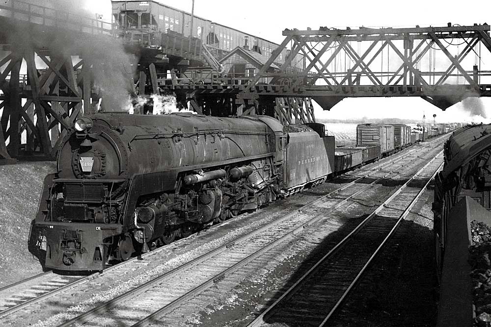 Steam locomotive with freight train under truss bridge