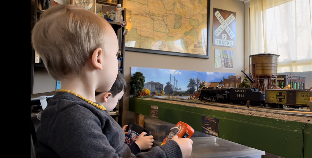two children watching toy train layout
