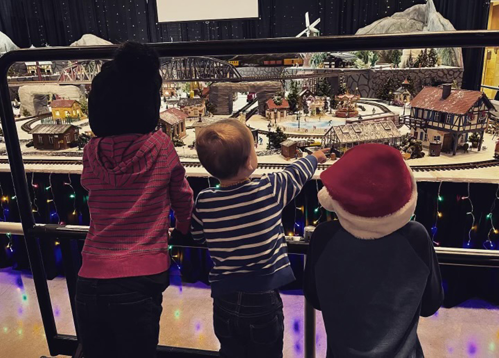 three children watching a train layout