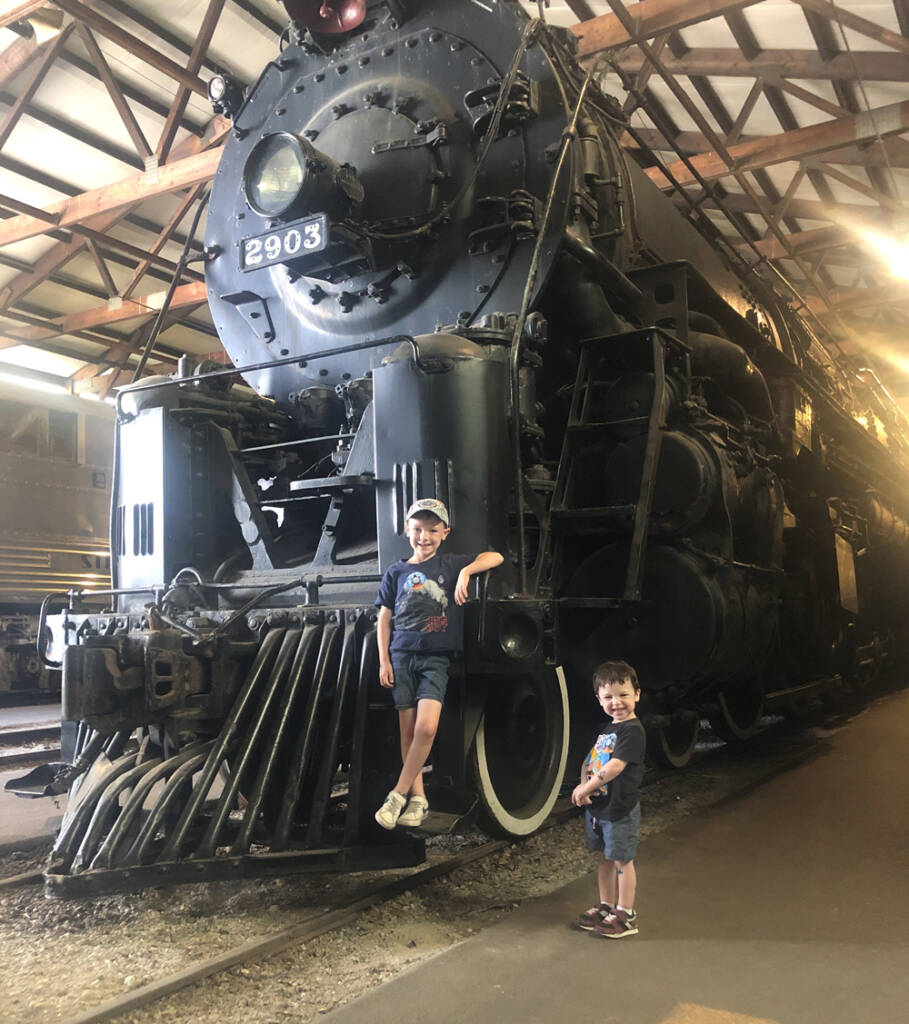 two children next to black steam locomotive