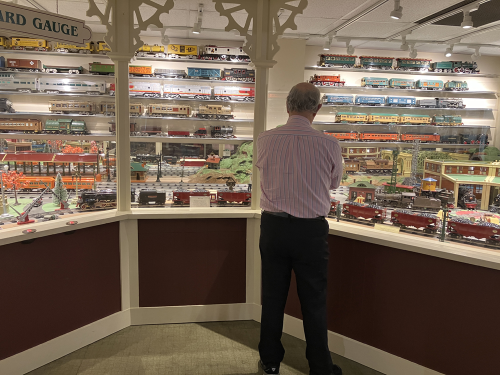man standing in front of toy train display