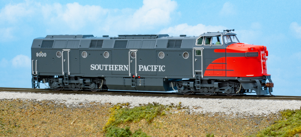 Color photo of gray and red HO scale locomotive on scenic base.