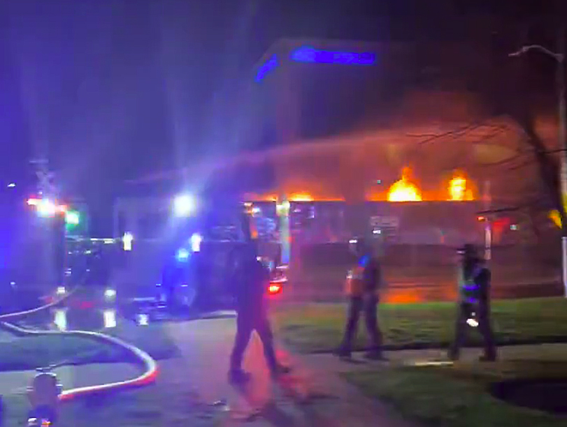 Night fire scene along railroad tracks. Fiery CPKC train rolls through London, Ontario