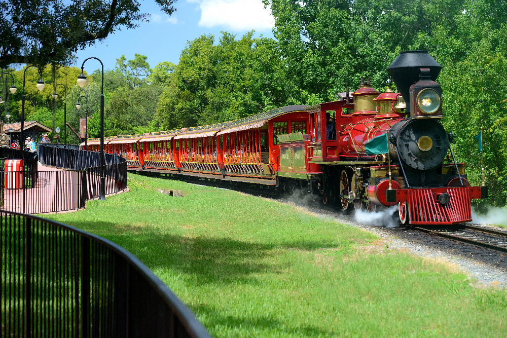 Small red steam locomotive pulling a train.