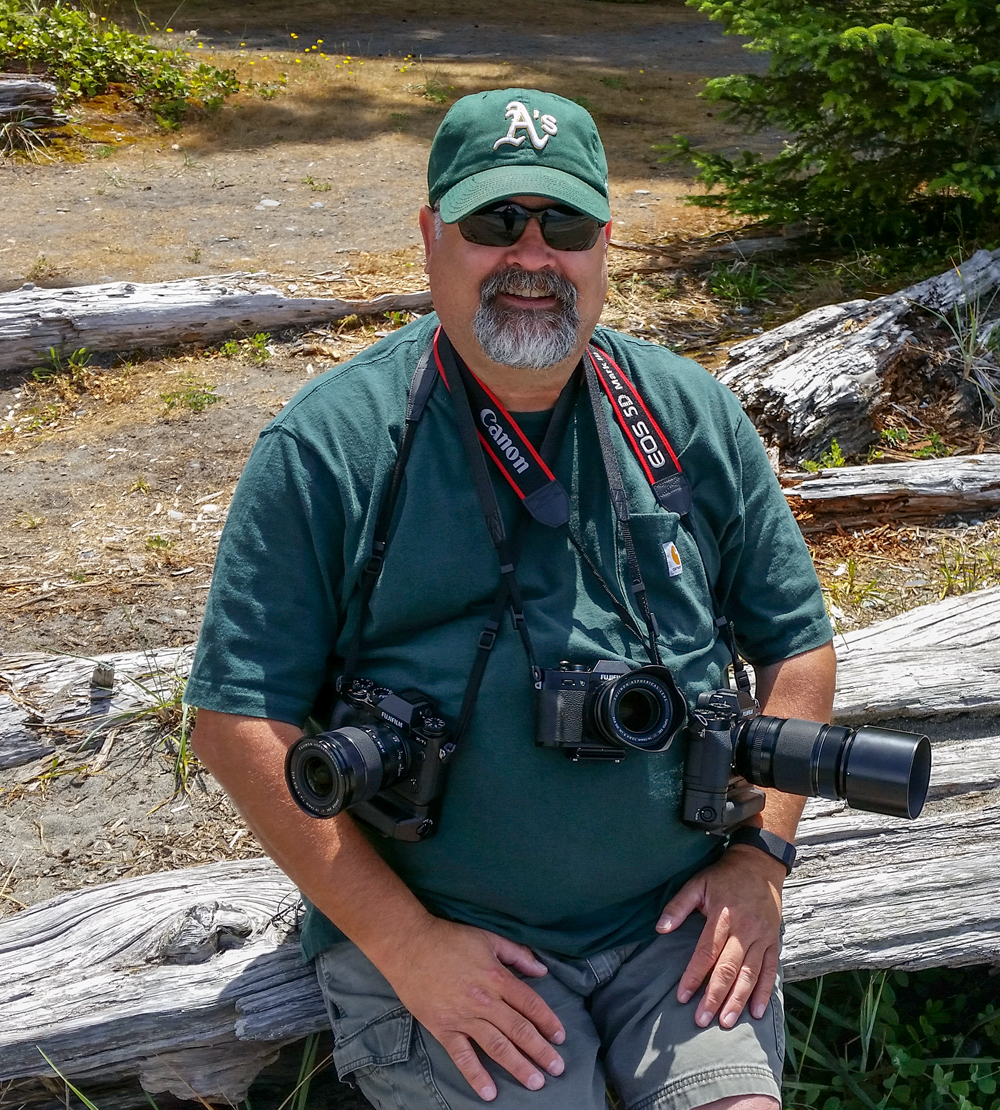 man in green with cameras