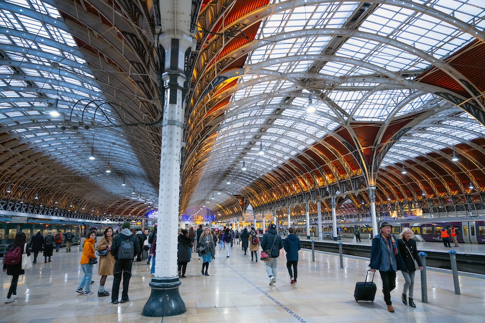 A glass roof supported by cast iron pillars supports a glass-roofed train station