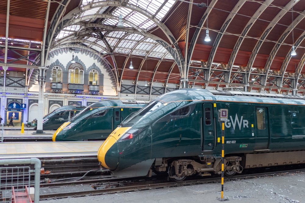 Three modern green-painted electric locomotives side by side in a station