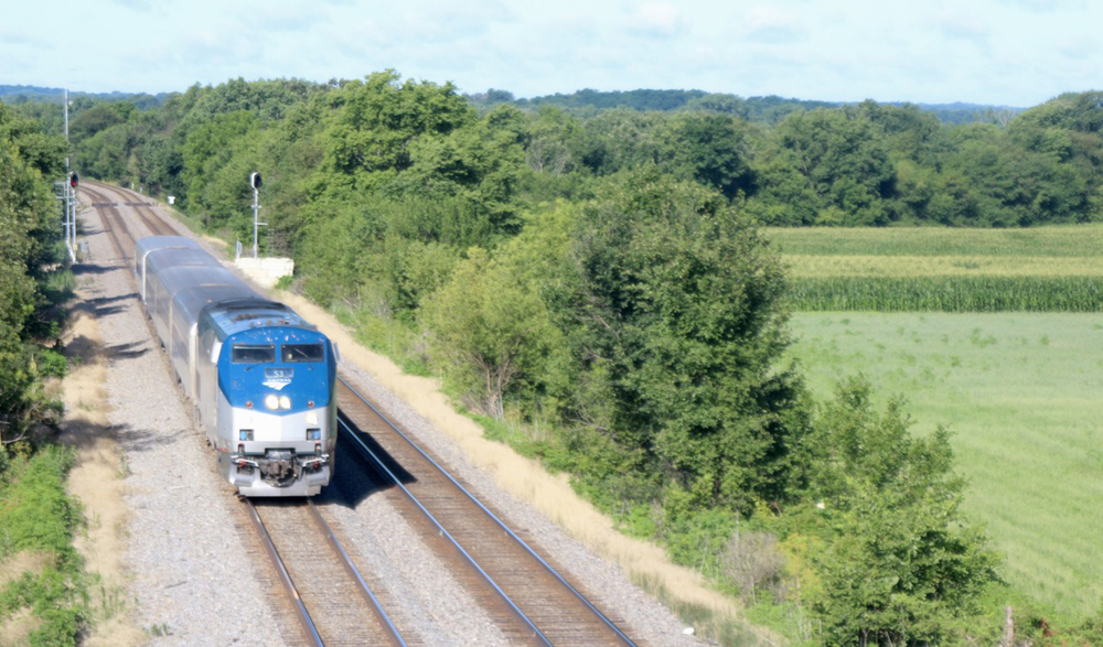 Passenger train on double-track main line with green field to the right