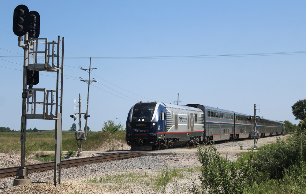 Passenger train crosses road and approaches signal