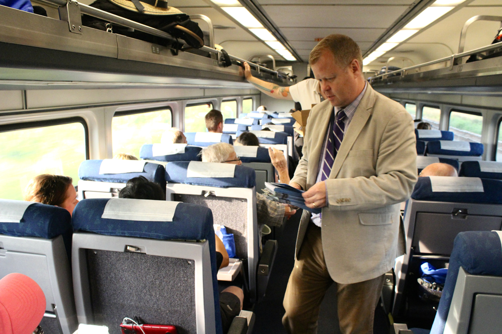 Man handing out brochures onboard train