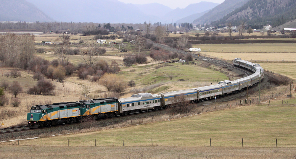 Passenger train with two locomotives and heritage equipment including four dome cars rounds curve