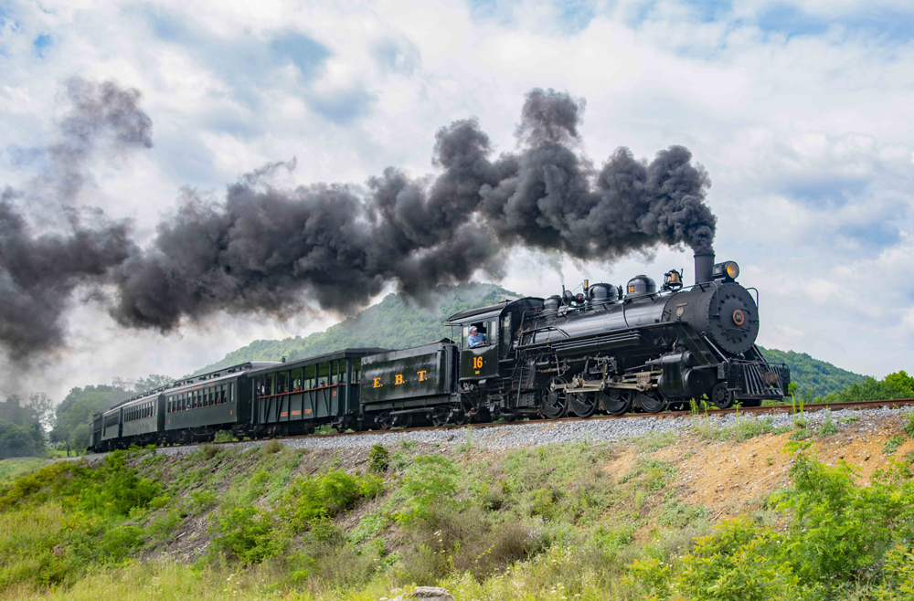 2-8-2 steam locomotive with passenger train on elevated curve