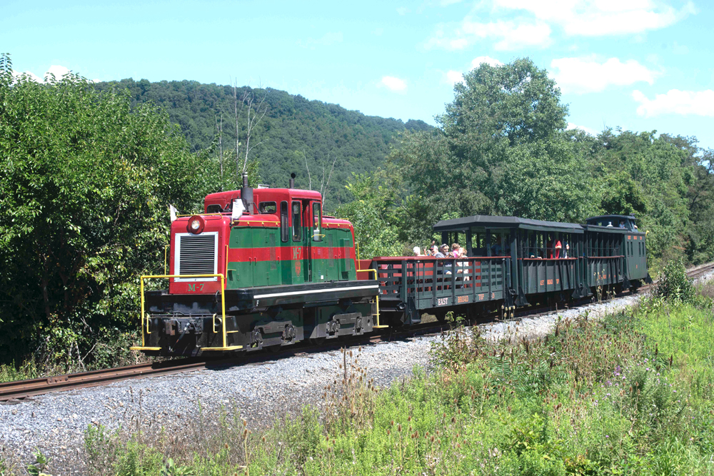 Red and green diesel locomotive with passenger train