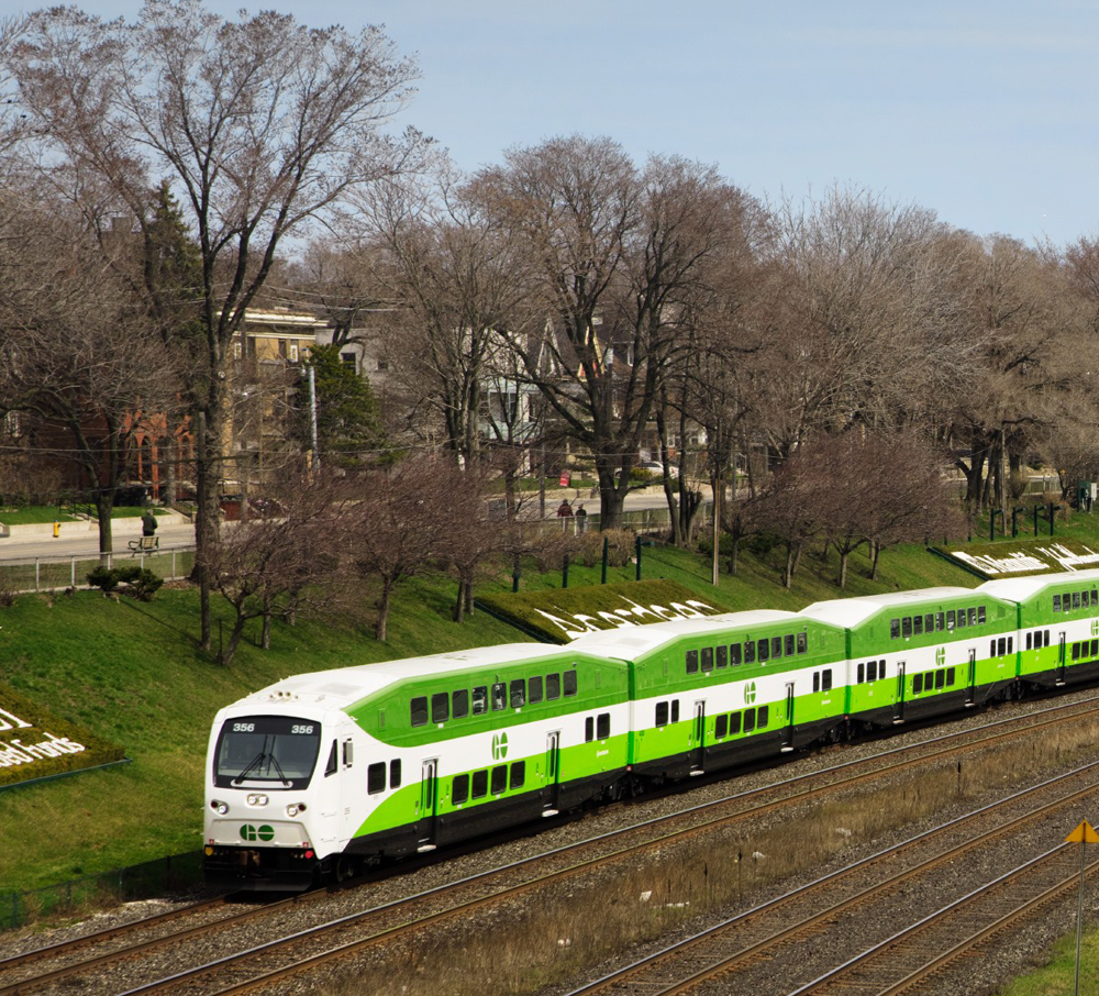 Green and white commuter train led by cab car
