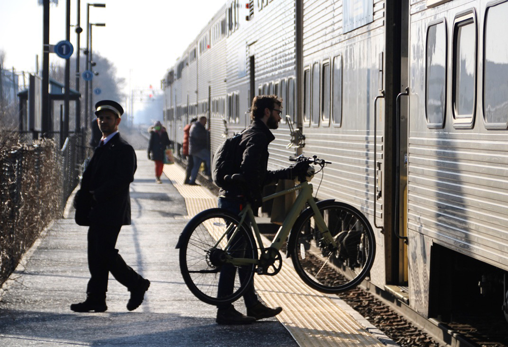 Man lifting bicycle onto train
