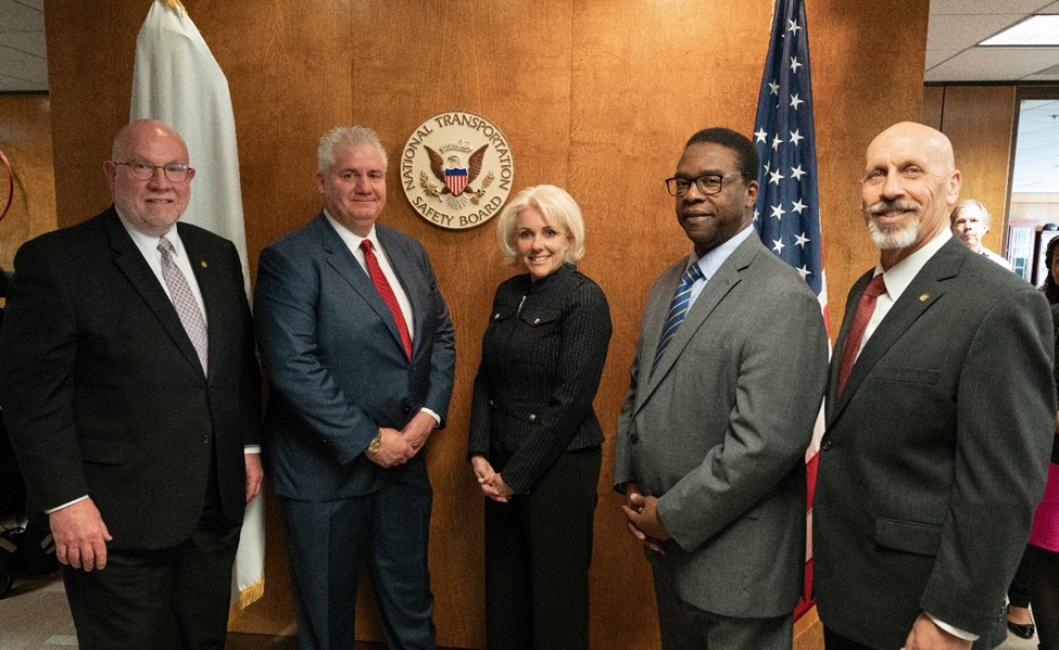 Five people posing in boardroom