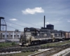 Black-and-white diesel locomotive with freight train in urban setting