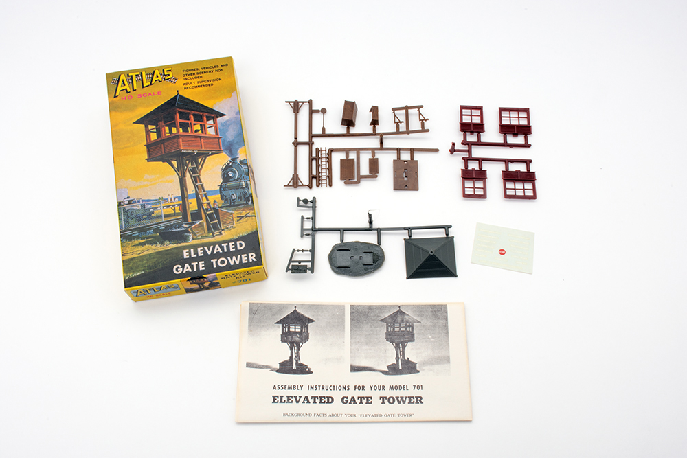 Small, colorful Atlas elevated gate tower box featuring a drawing of a model train elevated tower in red and brown with a blue sky behind it.