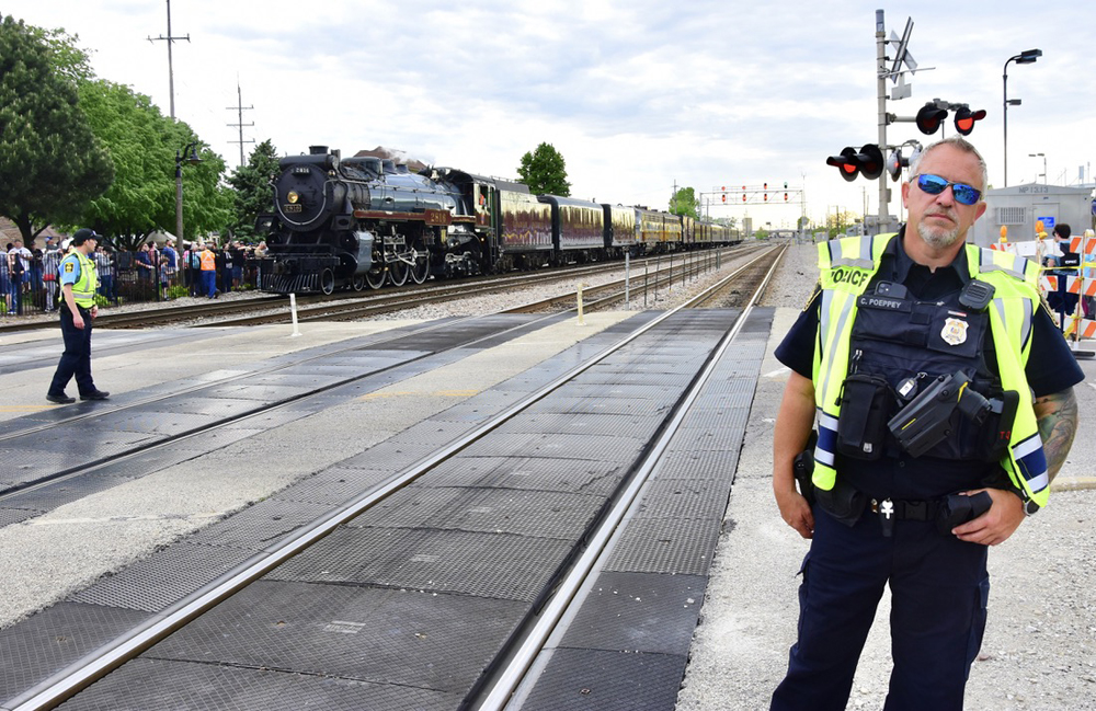 Police officer staring at photographer with steam locomotive in background