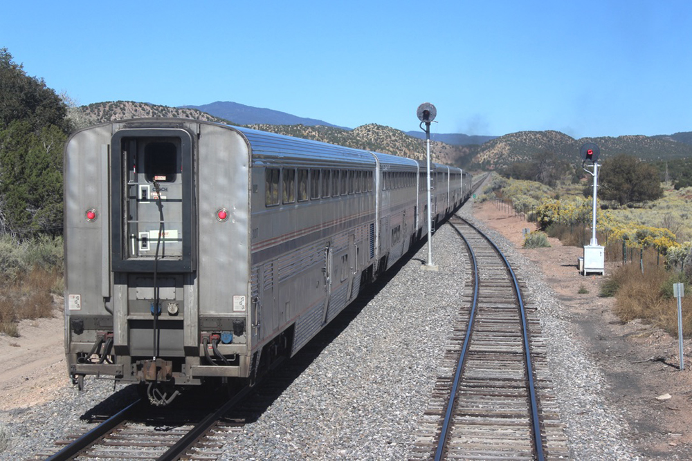 Rear end of passenger train with bilevel cars, as seen from another train