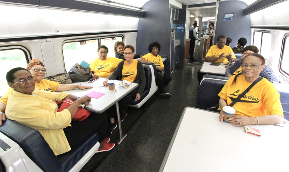 Women in matching yellow T-shirts at multiple tables in passenger car