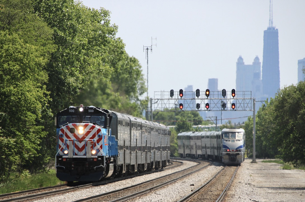 Two commuter trains meet with Chicago skylline in background