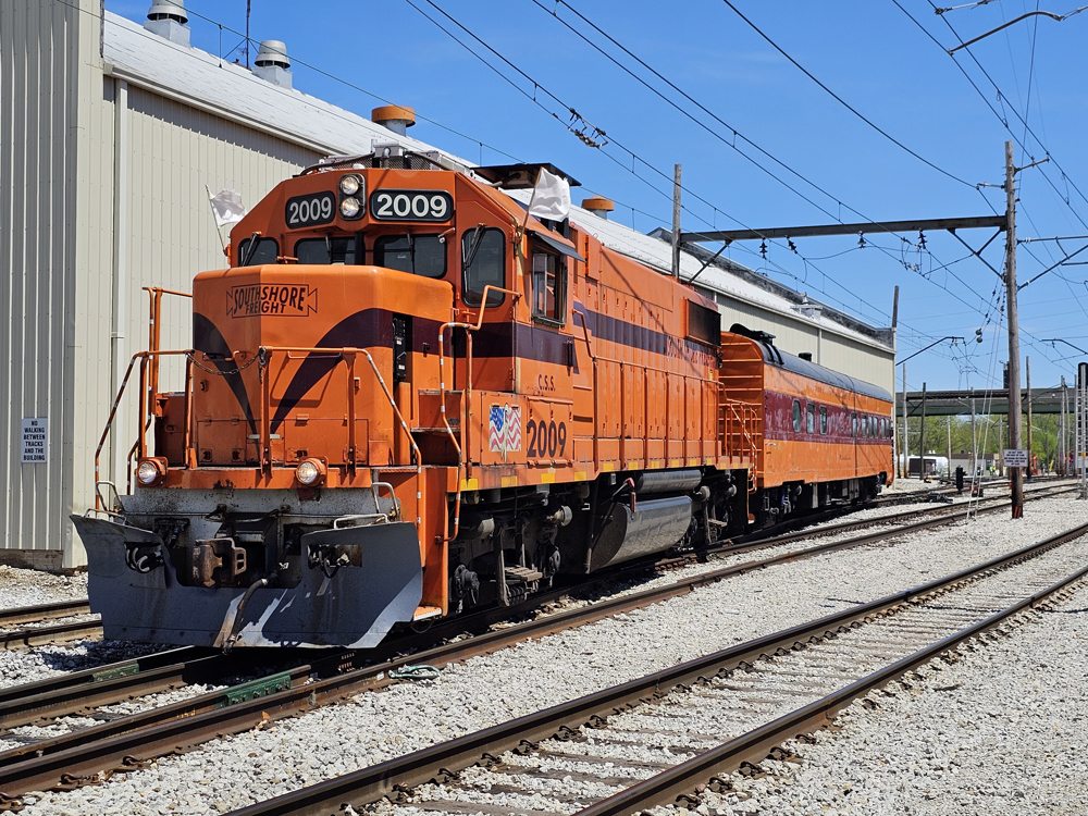 Orange and maroon locomotive and passenger car