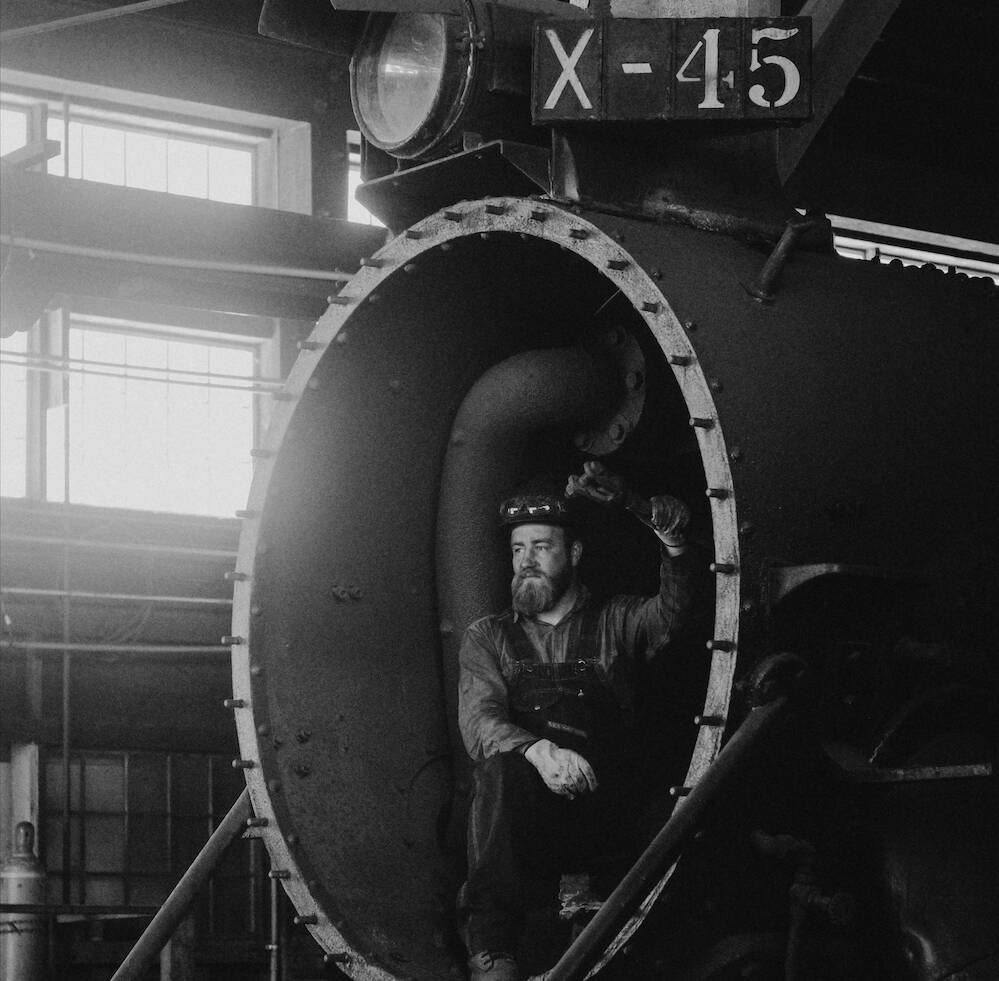 Black-and-white photo of Kyle Colley inside a steam locomotive as one of the young guns in preservation.